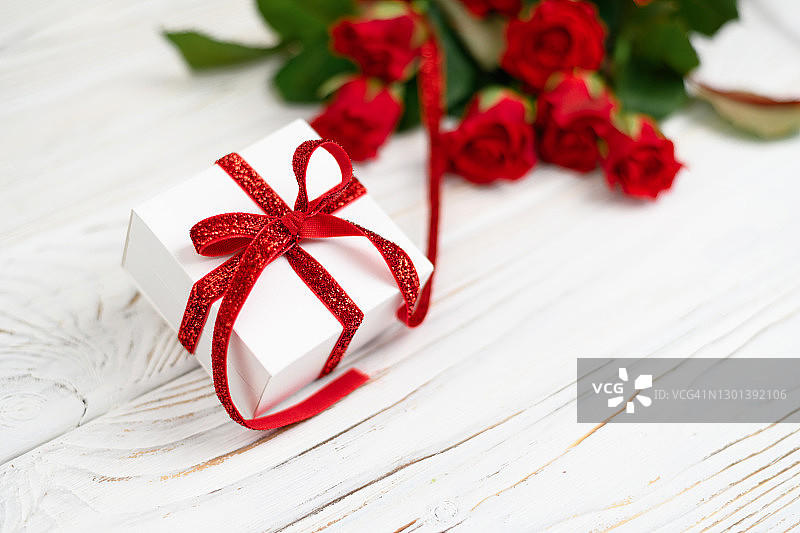 白色的礼盒，红色的蝴蝶结，红色的玫瑰和bokeh背景，祝贺圣瓦伦丁节，母亲节，3月8日图片素材