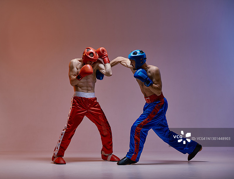 运动员打架，戴着拳击手套在红蓝工作室背景与拷贝空间，混合打架的概念图片素材