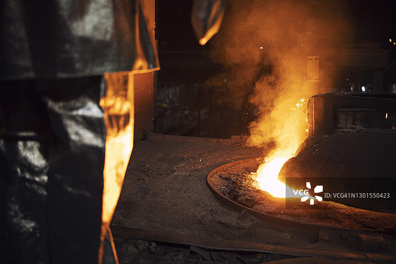 穿着防护服的工人在熔炉中控制铁的冶炼和加热矿石以提取铁基。图片素材