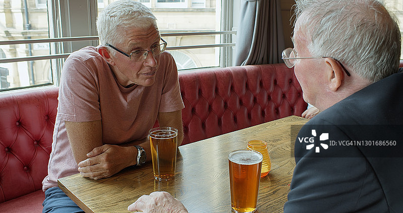 两个老男人在酒吧边喝啤酒边聊天图片素材