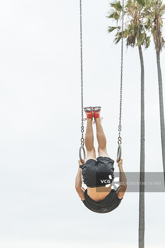 一个人倒挂在体操吊环上图片素材