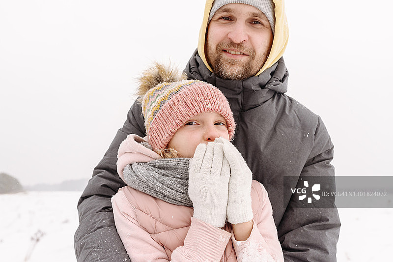 微笑的父亲和女儿站在晴朗的天空在冬天的特写图片素材