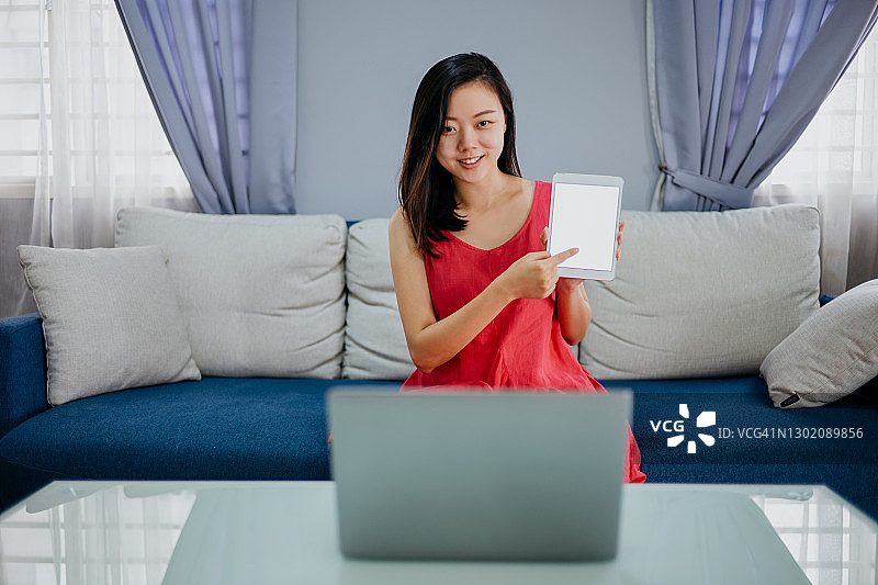 年轻的亚洲女性工作与笔记本电脑和数字平板电脑图片素材
