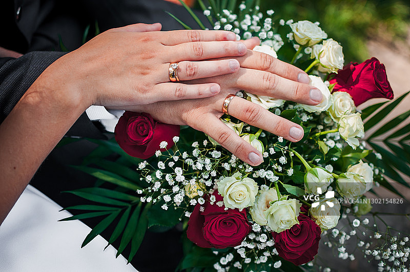在婚礼花束上，新婚夫妇手上戴着结婚戒指图片素材