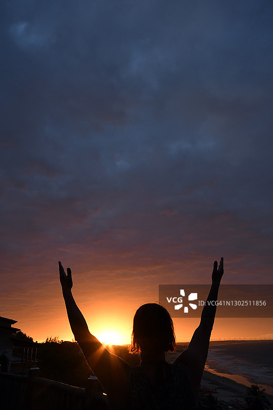 举起手臂看日落的女人。Lagoinha海滩。Paraipaba西阿拉,巴西。图片素材