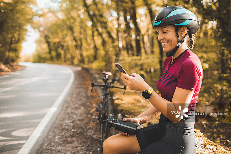 女人骑完自行车后休息，查看手机照片，微笑和大笑，通过视频与朋友交流图片素材