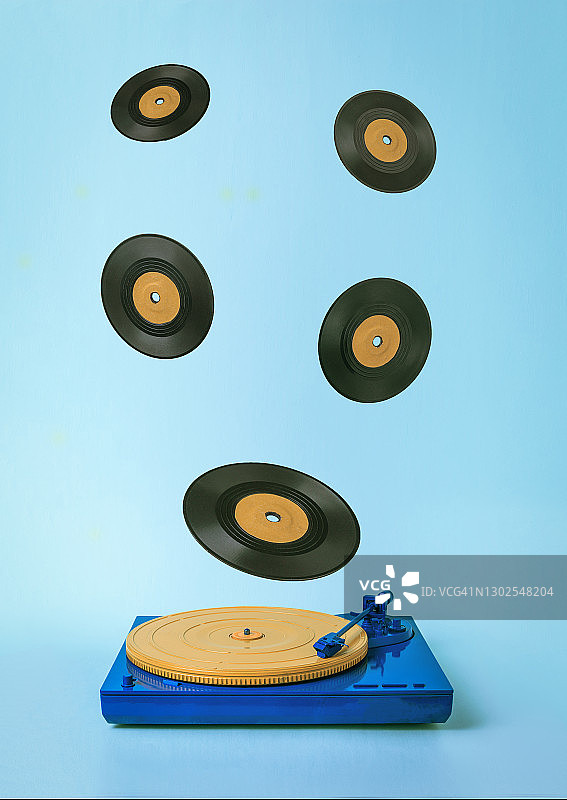 蓝色背景上有飞行乙烯基唱片的复古转盘。图片素材