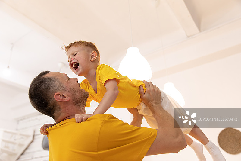 爸爸和儿子穿着黄色t恤。父亲怀里抱着一个小孩图片素材