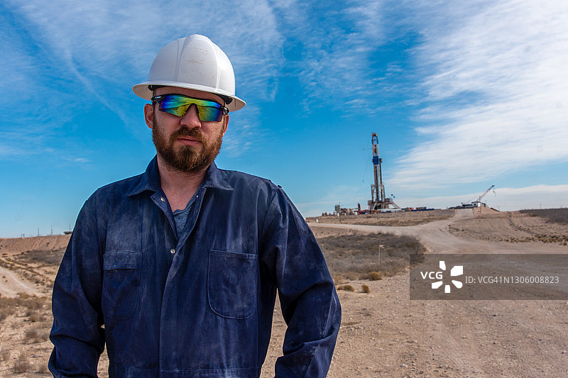 石油钻机工人与石油或天然气钻井平台在远处摆姿势图片素材