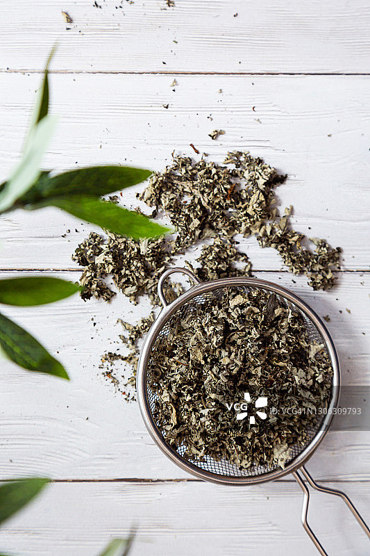 干覆盆子叶子在滤茶器特写。替代草药。健康的生活方式的概念。有机的，天然的草药茶放在一个轻木桌上。图片素材
