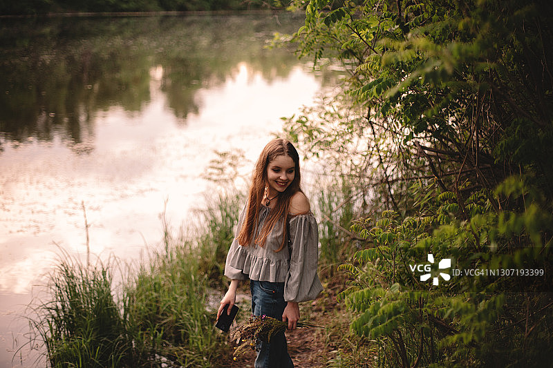 快乐的少女站在河边的森林在夏天图片素材