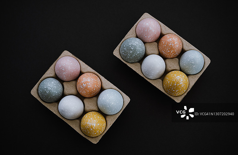 头顶上的彩色复活节彩蛋在黑色的蛋纸盒图片素材