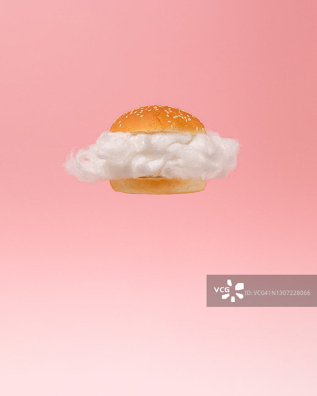 汉堡包里的白云在粉红色的背景下漂浮。超现实的快餐概念。最小抽象健康低热量食物的想法。图片素材
