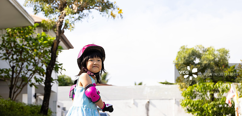 亚洲女孩骑着自行车戴着头盔和安全警卫。图片素材