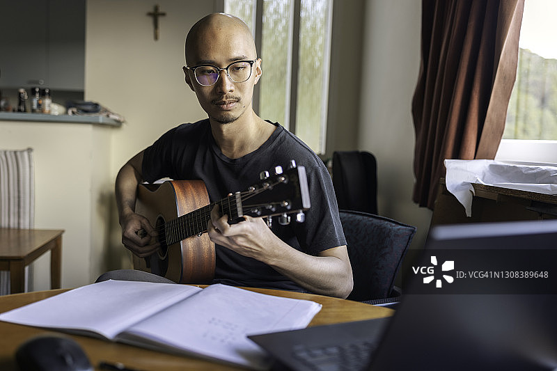 亚洲男子在家网上学习弹吉他图片素材