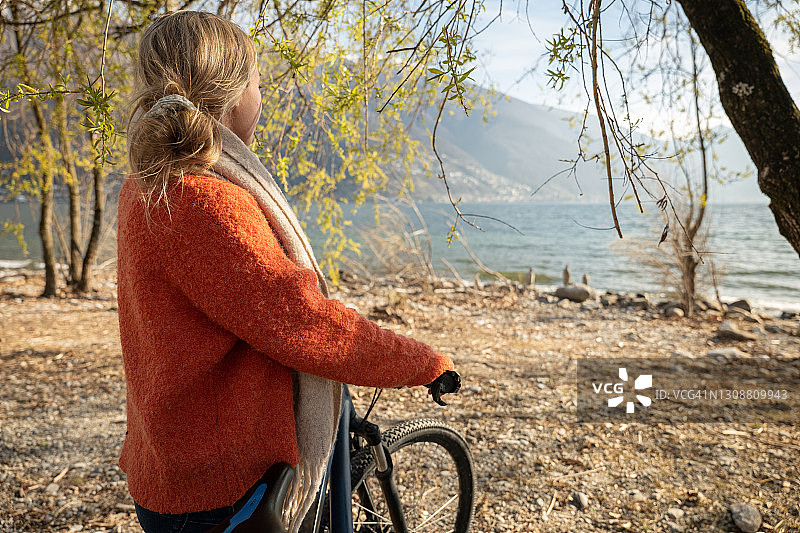 骑着自行车的女人在湖边和夕阳下凝视着大自然图片素材