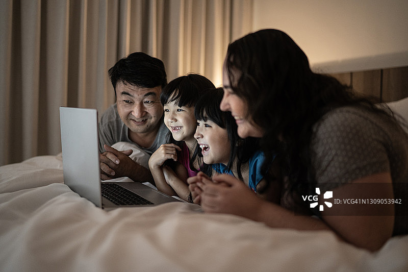 幸福的家庭躺在床上用电子平板电脑看东西图片素材