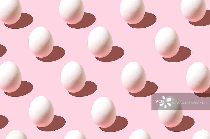 用白色复活节彩蛋做成的时尚图案，背景是淡粉色。图片素材