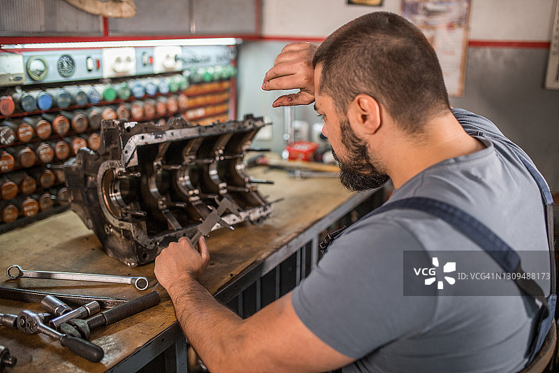 汽车修理工在汽车修理厂修理旧发动机图片素材