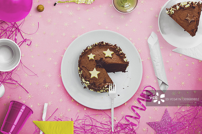 平铺巧克力蛋糕在粉红色的桌子聚会设置。图片素材