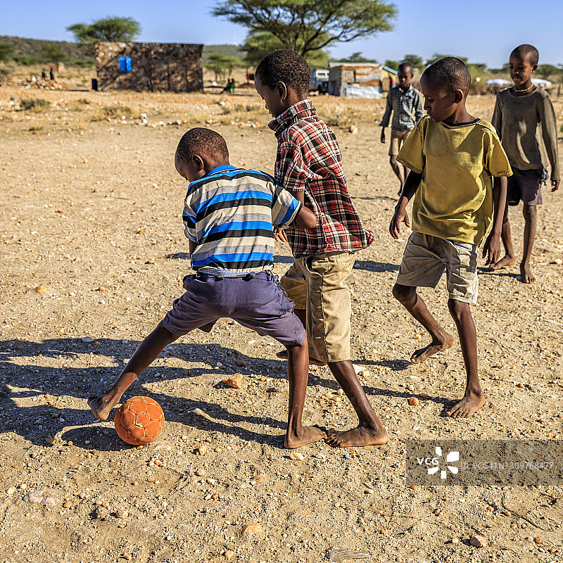 赤脚的非洲孩子在村庄里踢足球，东非图片素材