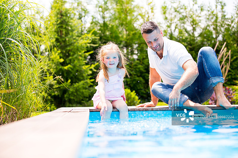 父亲和女儿在游泳池。图片素材