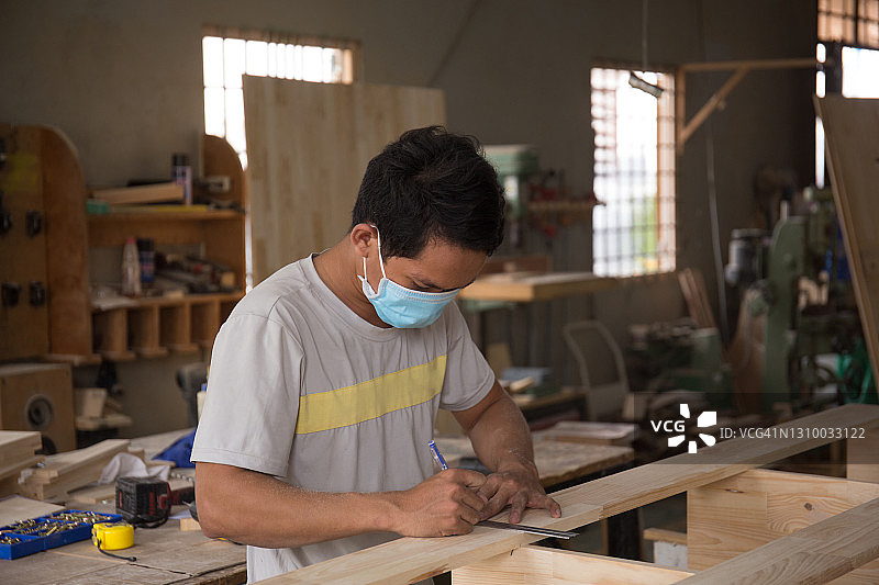 木工在车间用尺量木板。木制家具的细木工工作。中小企业的概念图片素材