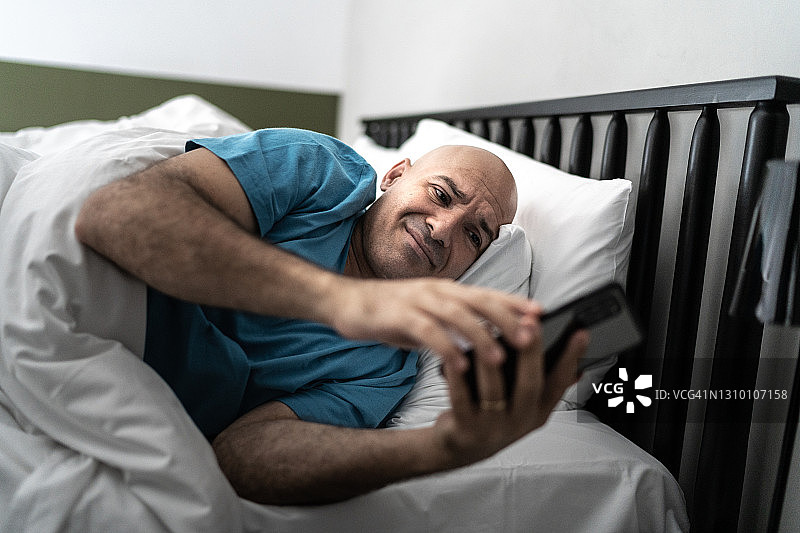 男人在床上看手机图片素材