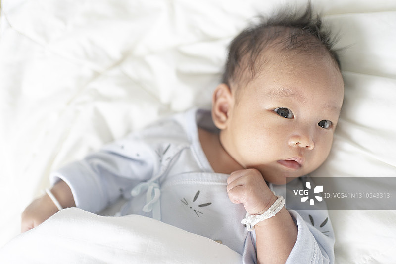 近距离观察女性可爱的亚洲新生儿躺在舒适的床上在家图片素材