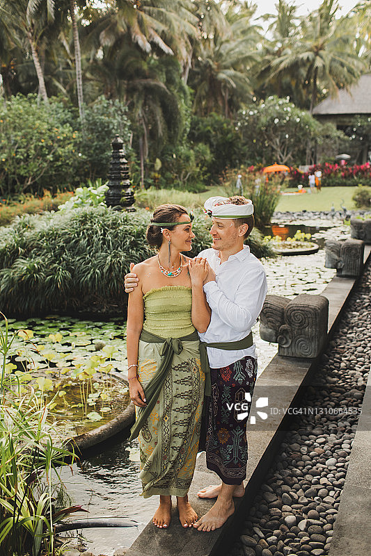年轻快乐的新婚夫妇穿着巴厘传统服饰。巴厘岛多元文化旅游婚礼。图片素材