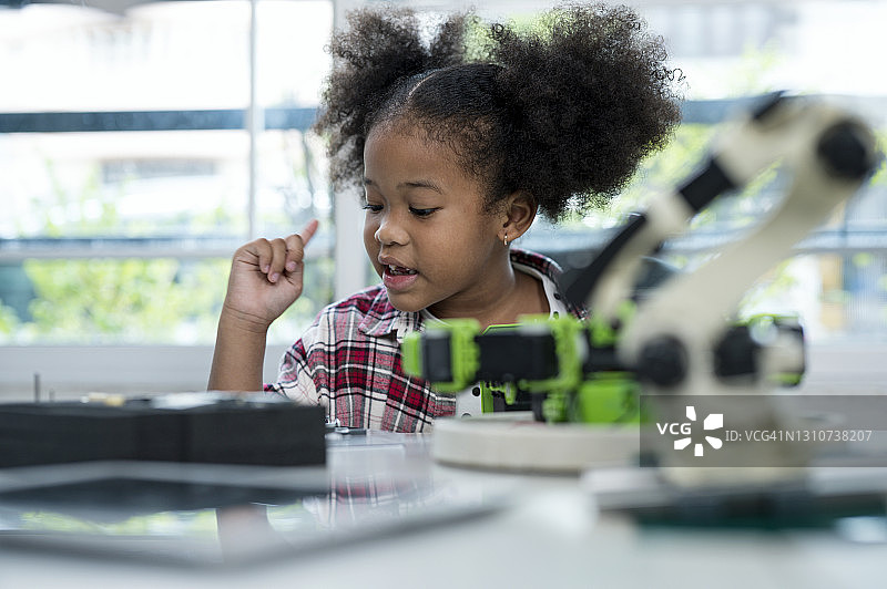 让孩子学习科技，提高技能和知识概念。非洲裔美国女学生喜欢在为孩子们选择组装机器人玩具的技术课上的零件。图片素材