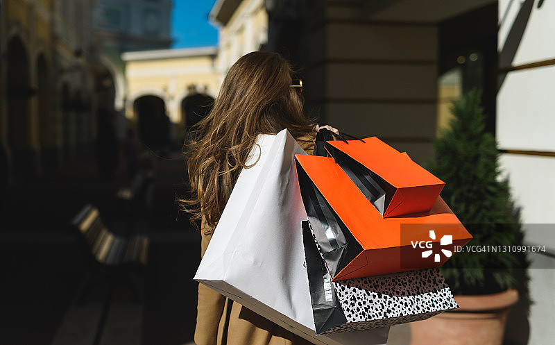 成功的购物!一个年轻迷人的欧洲女人手里拿着很多购物包从各种服装和鞋类商店图片素材