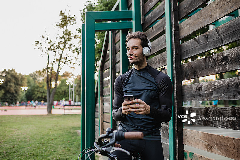 一个穿着运动服的年轻人在骑车休息时用手机图片素材
