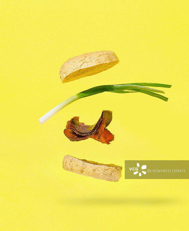 漂浮的汉堡，肉和青葱孤立在黄色的背景。食品的概念。图片素材