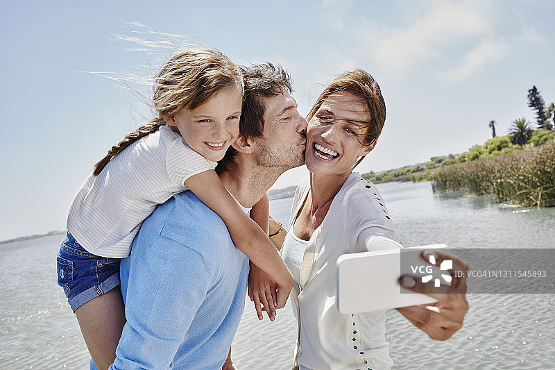 欢乐的一家人在湖边用手机自拍图片素材