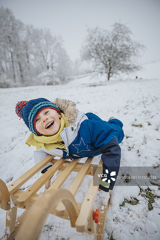 快乐的男孩在雪地上拉雪橇图片素材