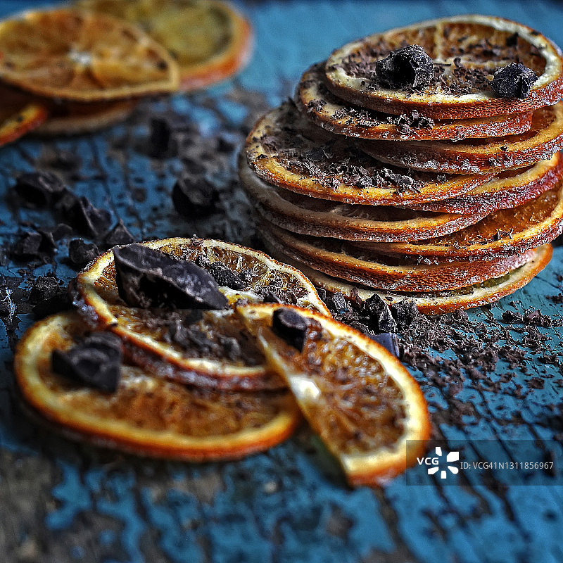 食物摄影的有机自制干橙水果片片与巧克力侧视图在乡村的蓝色木制背景近距离，微距摄影图片素材