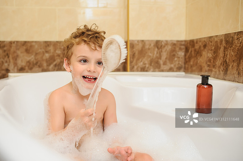 男孩在有泡沫和肥皂泡的浴缸里洗澡和玩耍图片素材