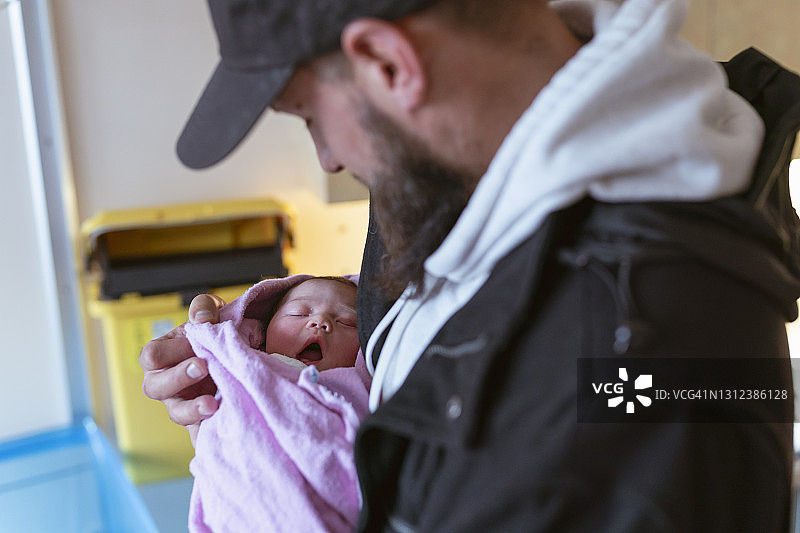 新爸爸抱着刚出生的女儿在医院分娩图片素材