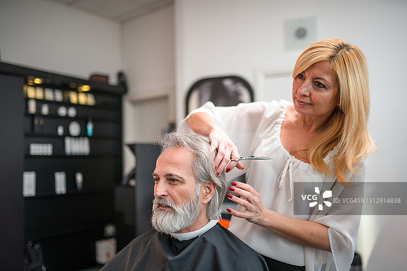 中年美发师做她的最后润色对一个灰色头发的客户图片素材