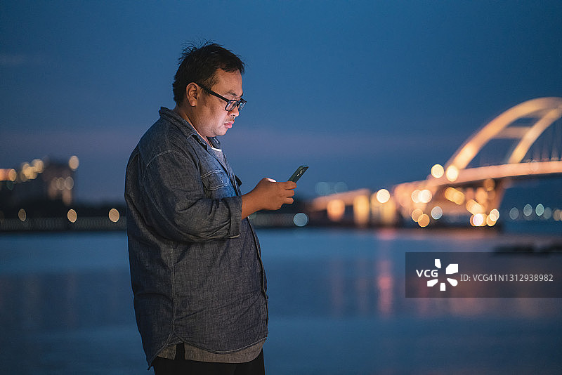 一个超重男人在海边看手机图片素材