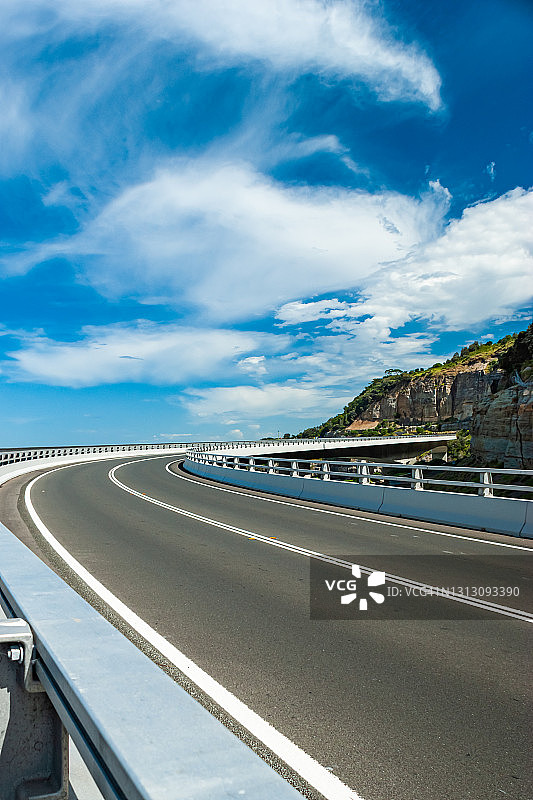 在一个阳光明媚的日子里，一座空荡荡的海洋公路桥弯弯曲曲地伸向远方图片素材