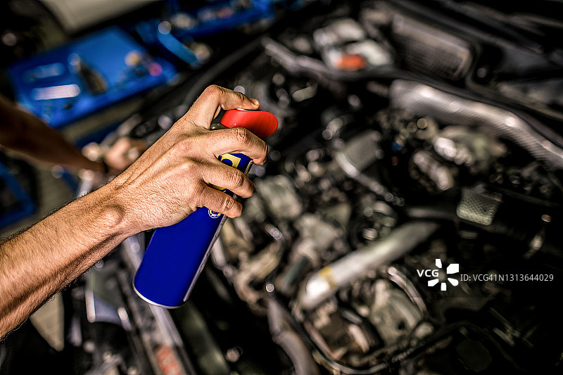 在修理厂用喷漆对汽车发动机进行机械清洗和润滑。图片素材