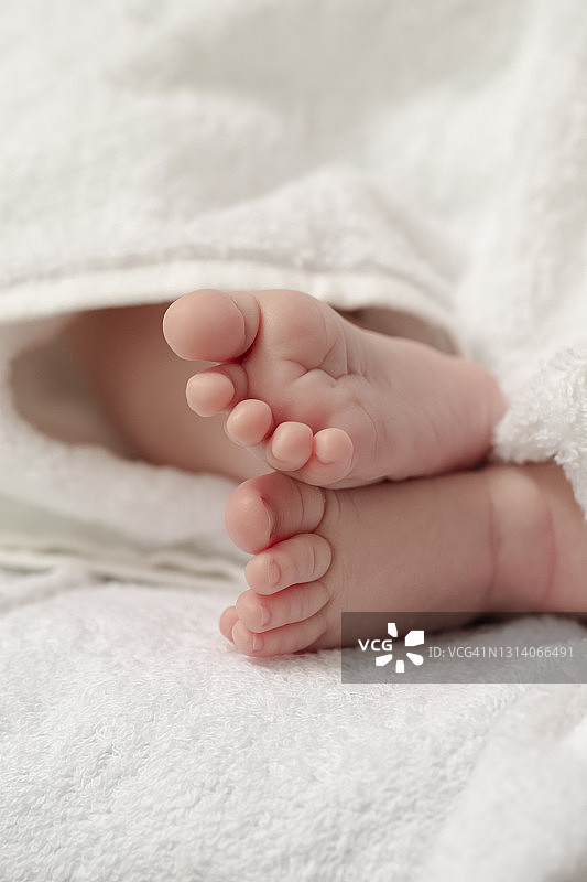 微距特写拍摄的一个四周大的男婴交叉的脚在白色毛巾。垂直的形象定位图片素材