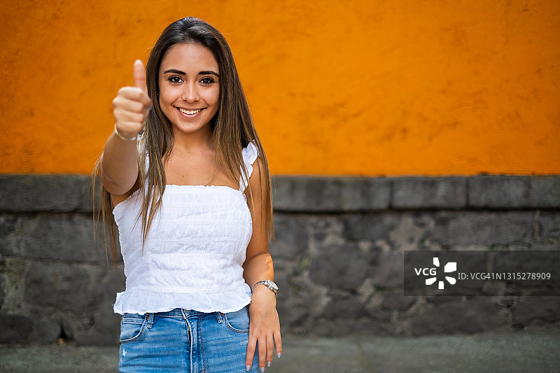 在墨西哥城，年轻的西班牙妇女看着镜头，竖起大拇指图片素材