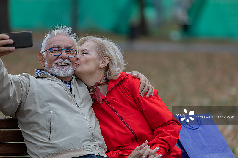 快乐的老年夫妇在城市公园一起度过一个美好的秋天，并拍摄他们自己。图片素材