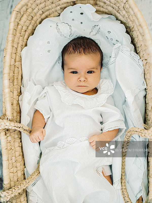 可爱的新生婴儿在他的稻草摩西篮子里醒来。图片素材