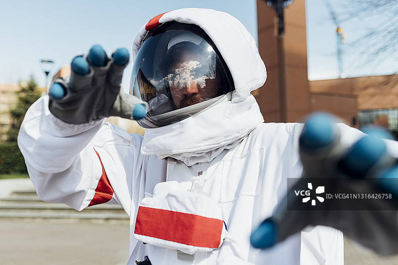 穿着太空服的年轻男性宇航员在户外做手势图片素材