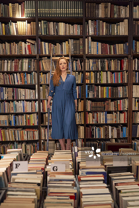 一个女人站在图书馆的书架上图片素材