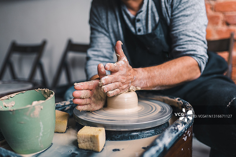 在陶器作坊里，男性的双手正在制作陶罐图片素材